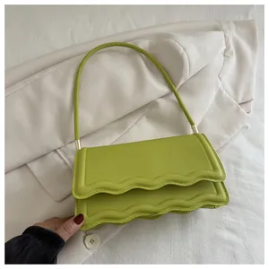 Dettaglio del design con bordo smerlato della borsa a tracolla in PU verde avocado