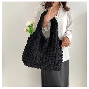 Macro view of black bubble textured shoulder bag with spacious interior and wide handle