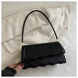 Dettaglio della borsa a spalla in PU nero con bordo a onde e hardware in metallo oro