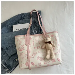 Dettaglio della borsa tote in pelle PU con motivi graffiti rosa e ciondolo a orsetto