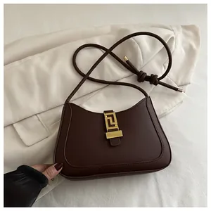 Close-up of matte dark brown leather bag featuring an elegant gold geometric buckle