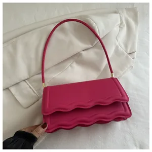 Dettaglio borsa a spalla fucsia con doppie patte ondulate e finiture dorate