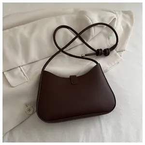 Deep brown saddle bag detail with knot shoulder strap on beige blazer background