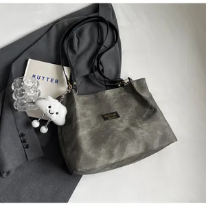 Détail d'un sac cabas texturé vintage avec pendentif nuage sur fond de blazer gris