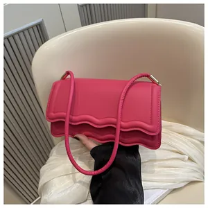 Dettaglio della borsa a spalla rosso rosa con patta a onde e fibbie in metallo dorato