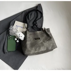 Détail du sac cabas gris texturé avec pendentif nuage et étiquette de marque