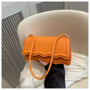 Dettaglio del bordo ondulato smerlato su questa borsa a spalla in pelle PU arancione vivace