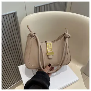 Detail of milk tea leather shoulder bag with Greek fret gold buckle and knotted strap