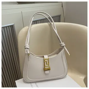 Detailed view of cream baguette bag with vintage gold buckle and knotted twin shoulder straps