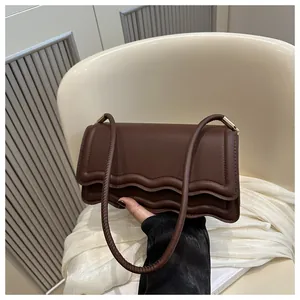 Dettaglio della borsa a tracolla marrone scuro con patta a onde e cuciture fini