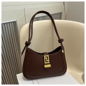 Detail of dark brown crescent bag with gold rectangular buckle and knotted strap accents