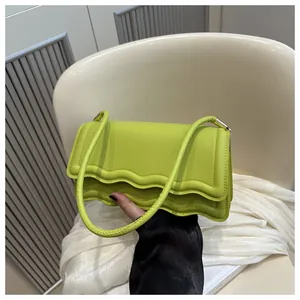 Dettaglio della borsa a tracolla verde neon con bordi ondulati e trama in pelle PU