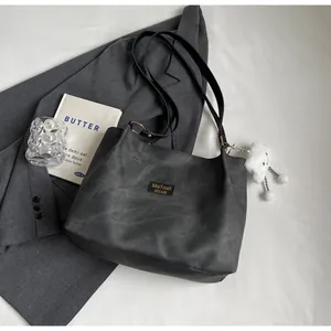 Vue détaillée du sac cabas gris foncé avec pendentif nuage en peluche et logo cousu