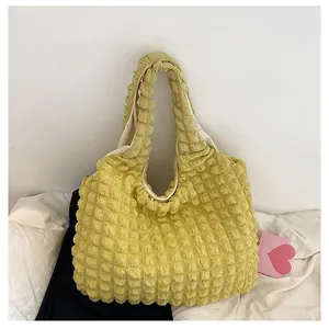 Detail of a yellow bubble textured tote bag with puffy fabric handles and soft lining