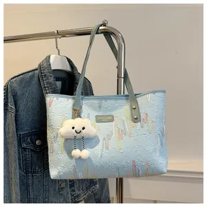 Close-up of light blue tote bag with colorful wave embroidery and white cloud charm