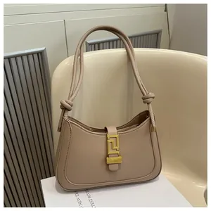 Detail view of the retro beige underarm bag featuring a gold buckle and knotted shoulder strap