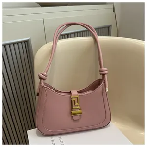 Detailed close-up of pink shoulder bag with gold geometric buckle and knotted strap accents