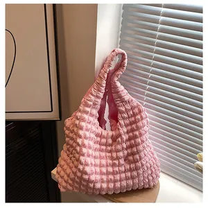 Detailed close-up of light pink bubble textured fabric and handle on a fashion tote bag