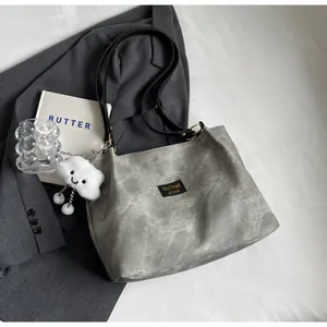 Détail du cabas gris texturé avec étiquette de marque et breloque nuage blanc
