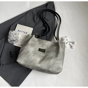 Vue à plat d'un sac cabas gris texturé avec des anses noires et un blazer assorti