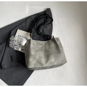 Détail du sac cabas gris à motif marbré avec breloque ours sur tissu blanc