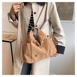 Détail du sac bandoulière kaki avec texture nuage et breloques papillons argentées