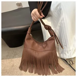 Detalle del bolso hobo de cuero marrón oscuro con flecos largos y correa de hombro anudada
