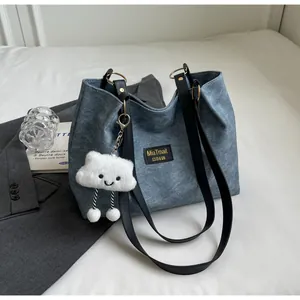 Détail d'un cabas en denim bleu avec un charmant nuage en peluche blanc et des anses noires