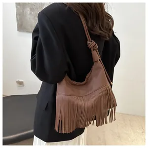 Detalle del bolso de hombro en cuero marrón con flecos y correa con nudo elegante