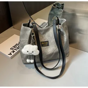 Détail du cabas en toile grise avec lanières en cuir noir et pendentif nuage