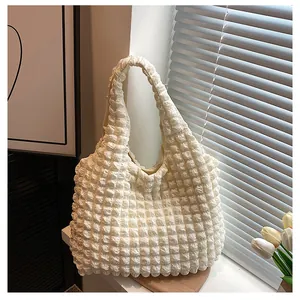 Detailed view of white bubble textured tote bag on wooden tray with natural window light