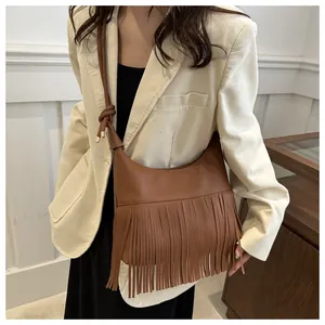 Detalle de bolso bandolera marrón con flecos largos y correa anudada en piel granulada
