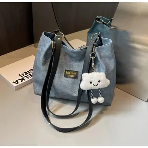 Détail du sac cabas en denim bleu avec étiquette noire et pendentif nuage en peluche