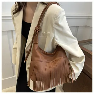 Detalle de bolso hobo marrón caramelo con flecos densos y correa de hombro anudada