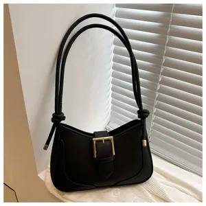 Détail du sac croissant noir avec boucle dorée sur un vêtement en maille blanche