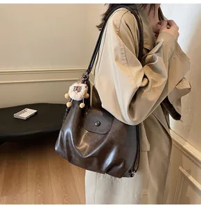 Detail of vintage dark brown tote bag with high-quality PU texture and cute lion charm