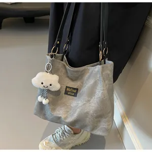 Détail d'un grand sac fourre-tout gris avec anses noires et charmant porte-clé nuage