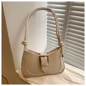 Détail du sac croissant crème avec boucle dorée et bandoulière à nœuds élégante