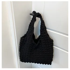 Detail of black pleated bubble tote bag with textured fabric hanging on a door handle