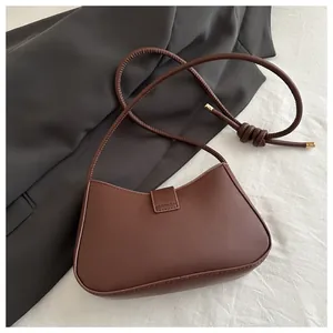 Détail du sac demi-lune marron foncé en similicuir avec rabat magnétique et bandoulière nouée