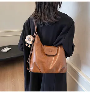Rear view of model carrying a large vintage brown leather tote bag with a lion plush toy charm