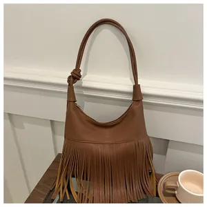Detalle del bolso de cuero marrón con textura de lichi, flecos y correa con nudo