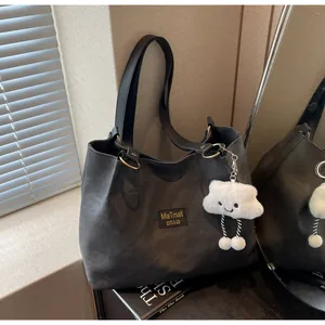 Détail du cabas gris foncé avec étiquette MiaTmait et pendentif en peluche nuage blanc