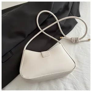 Détail du sac demi-lune crème avec bandoulière nouée et finitions métalliques dorées
