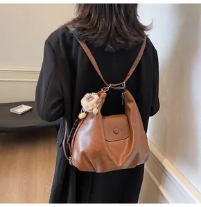 Detail of retro brown tote bag used as a backpack featuring a plush lion charm