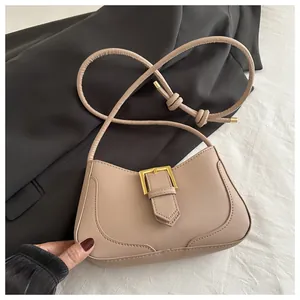 Détail du sac croissant beige avec boucle dorée sur fond de tissu texturé élégant