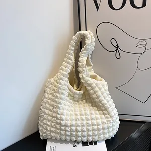 Chic cream bubble texture tote bag with stylish popcorn pleats displayed on a white stand