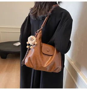 Detail of vintage brown faux leather tote bag with cute plush lion charm on strap
