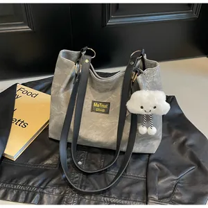 Détail du sac cabas en toile grise avec lanières en cuir noir et breloque nuage