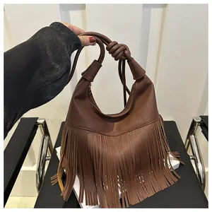 Detalle de bolso hobo marrón de cuero con patrón de lichi, flecos largos y asa anudada